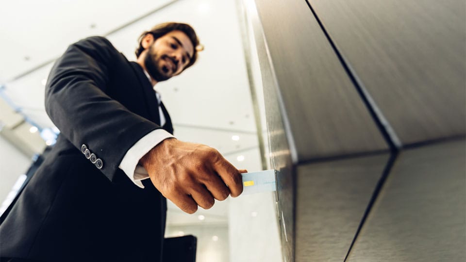 Businessman using card to open automatic gate machine in office building
