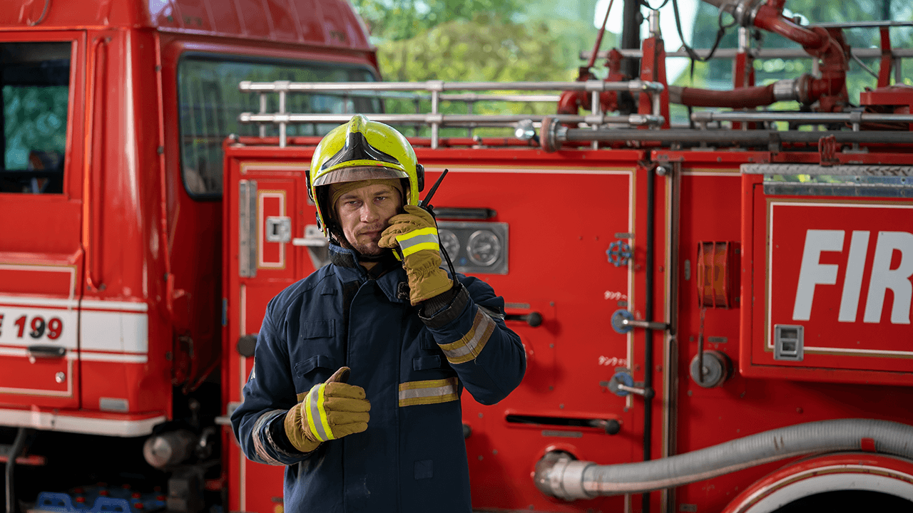 Fireman in a protective uniform standing next to a fire truck